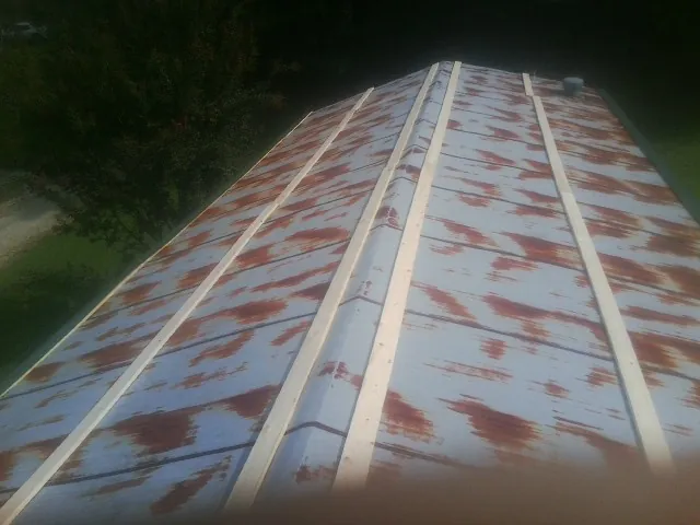 Rusted metal roof panels with new wood purlins before replacement — Storm Damage Roof Repair in Duck Creek Village by Roofing Brothers