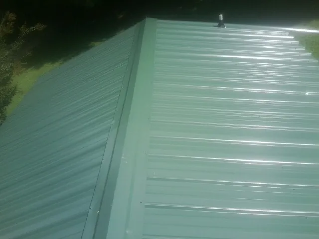 New green metal panels meeting at the ridge of a roof — Flat Roof Repair work by our crew in Duck Creek Village