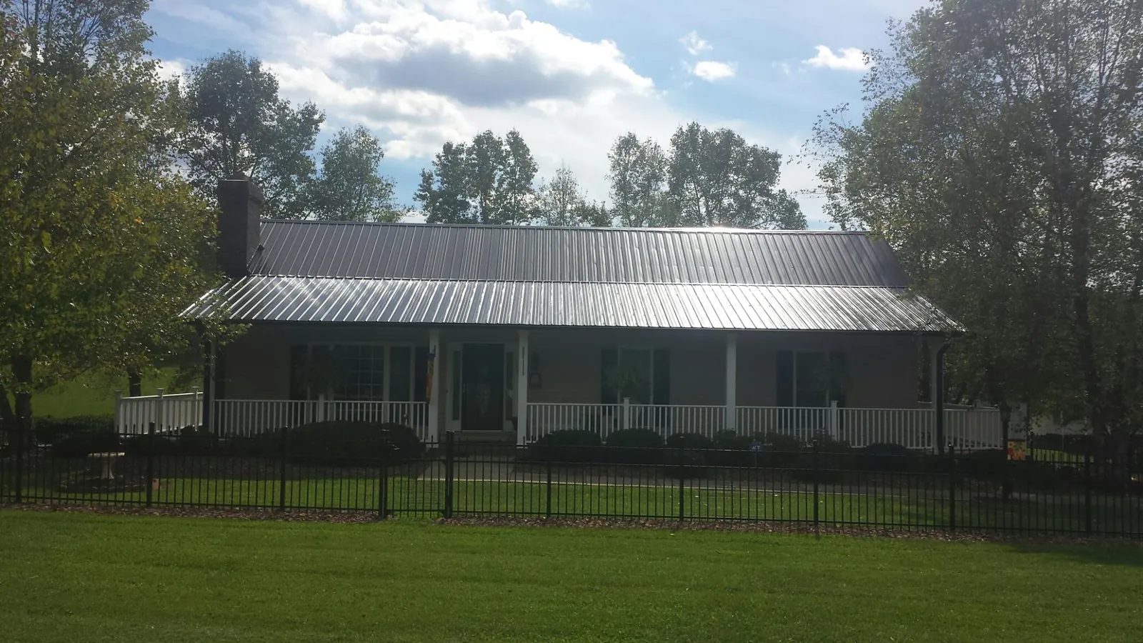 Gray metal roof on a brick ranch with a full width front porch — Gutter Guard Installation work by our crew in Duck Creek Village