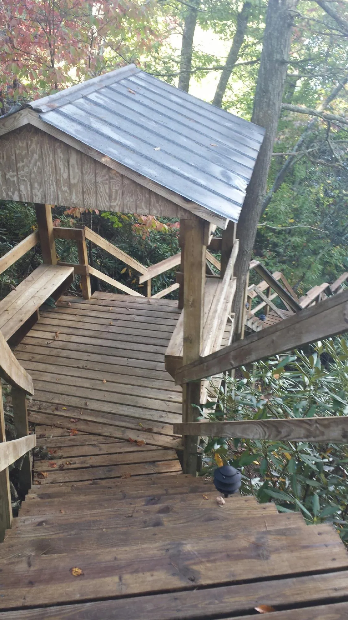 Metal roofed shelter over wooden steps on a wooded walkway — Skylight Repair & Installation work by our crew in Duck Creek Village